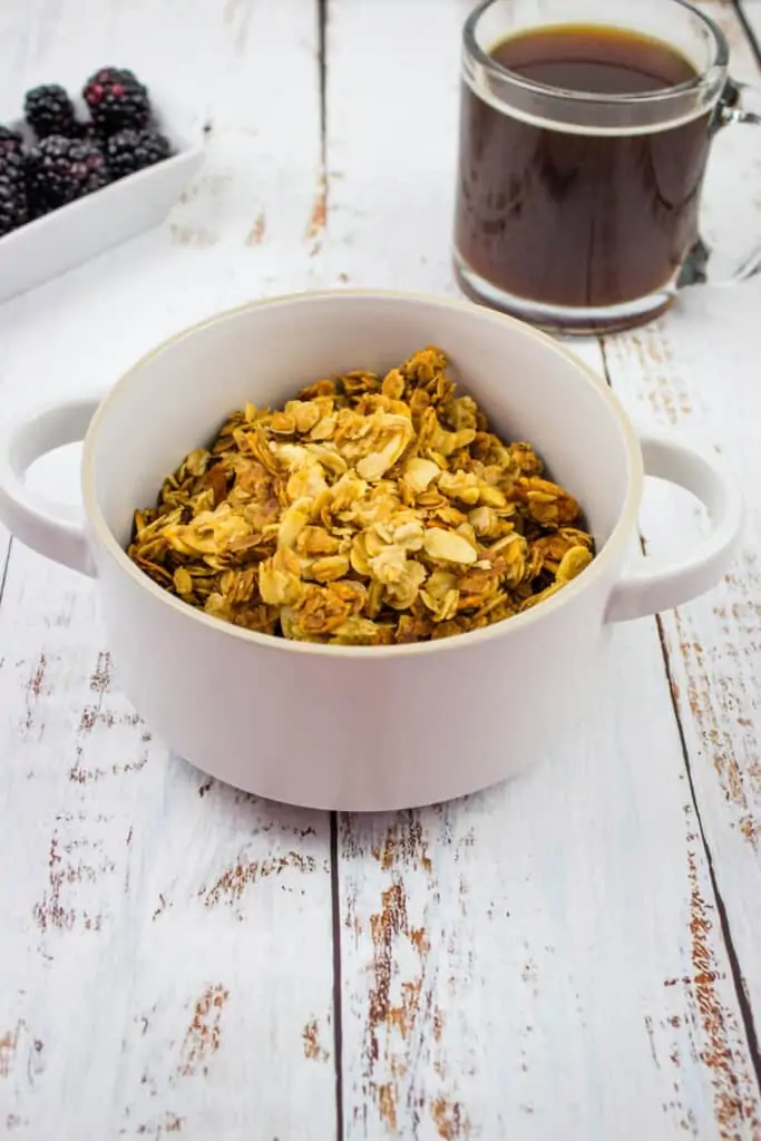 honey almond granola in a gray bowl with a coffee in the background