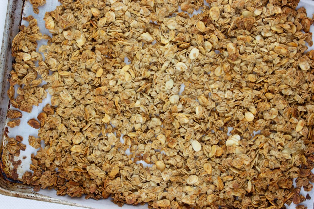 fully baked honey almond granola on a sheet pan that's golden brown around the edges