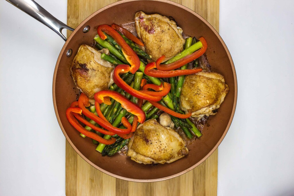 asparagus and red pepper added to chicken in the skillet