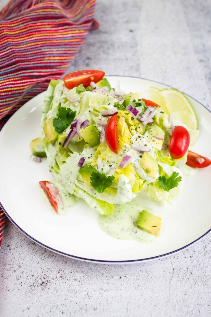 Creamy jalapeno dip on a wedge salad on a plate.