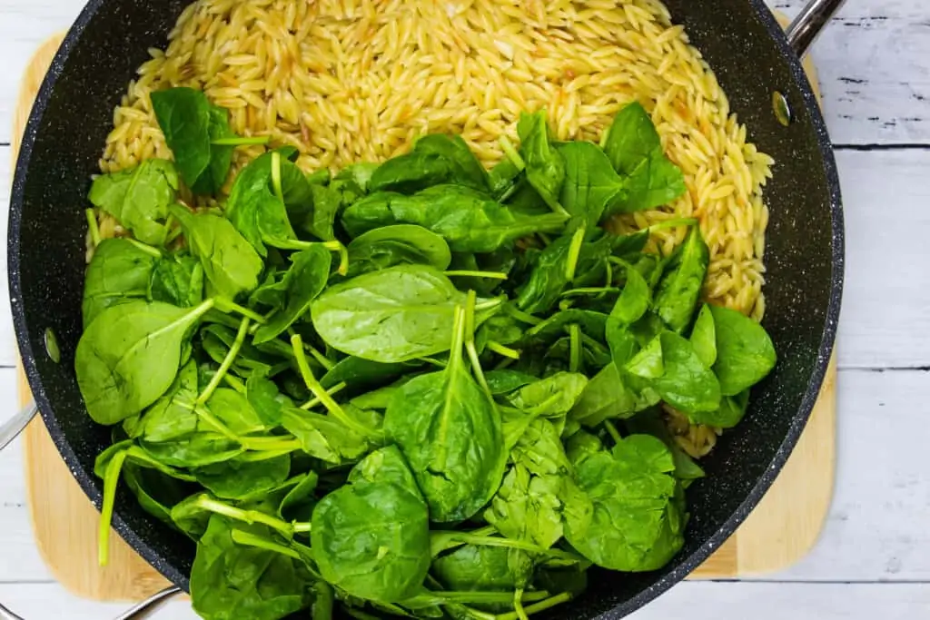 Folding the raw spinach into the hot orzo.