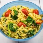 creamy spinach orzo with tomatoes in a blue serving bowl