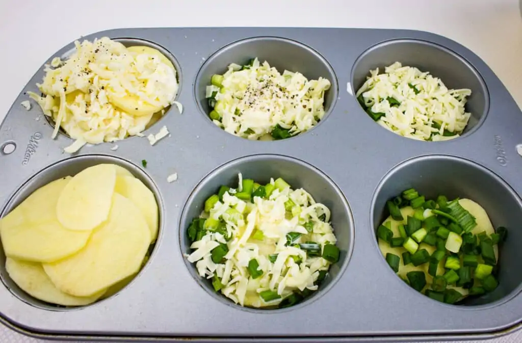 a jumbo muffin pan filled with au gratin potatoes gruyere in various stages of the layering process