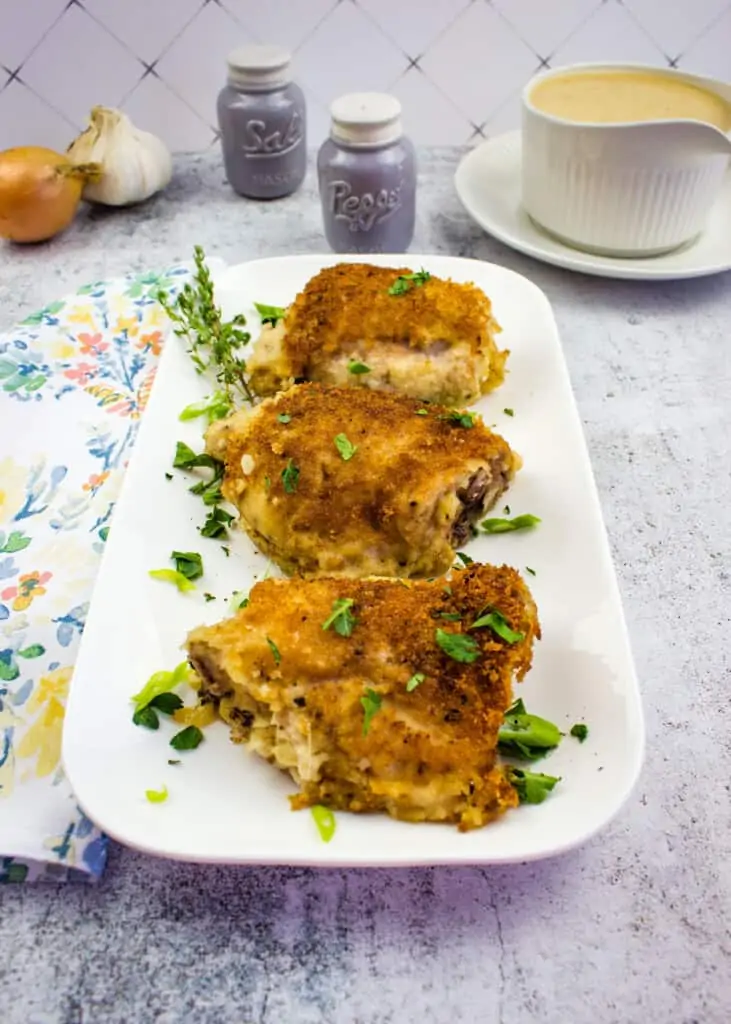 oven baked chicken thighs on a platter with gravy in the background