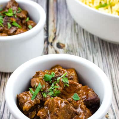 Authentic Hungarian Goulash in white serving bowls with spaetzel in the background
