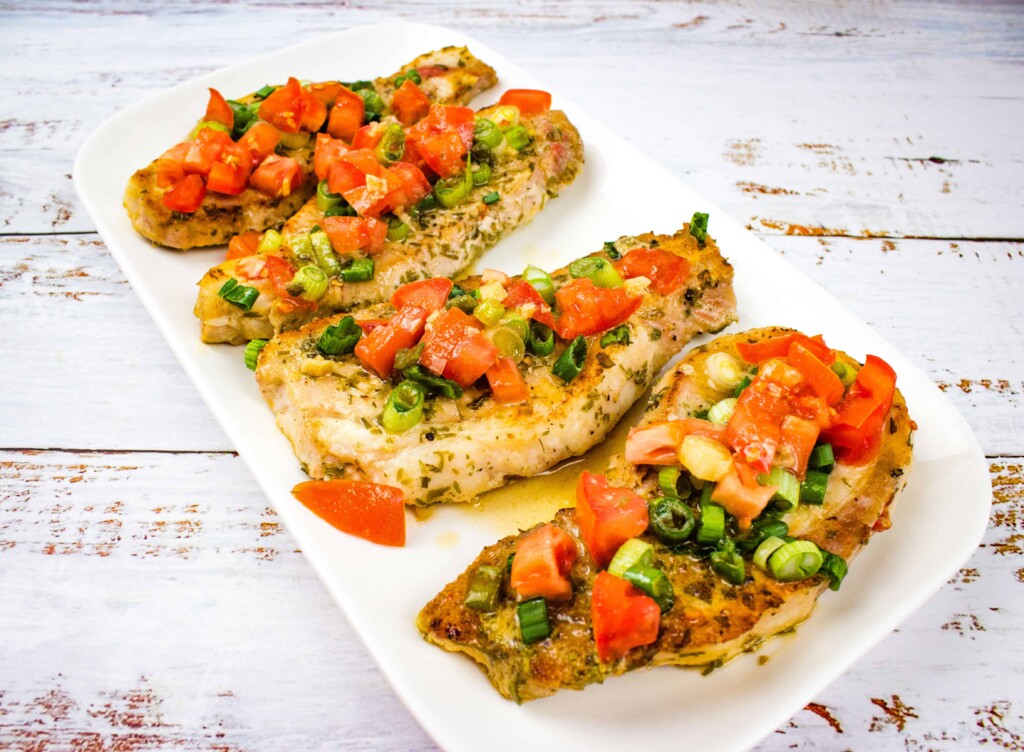 pork chops with tomato & green onion relish on a white platter