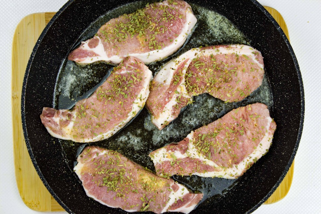 seasoned pork chops in a skillet ready to be seared