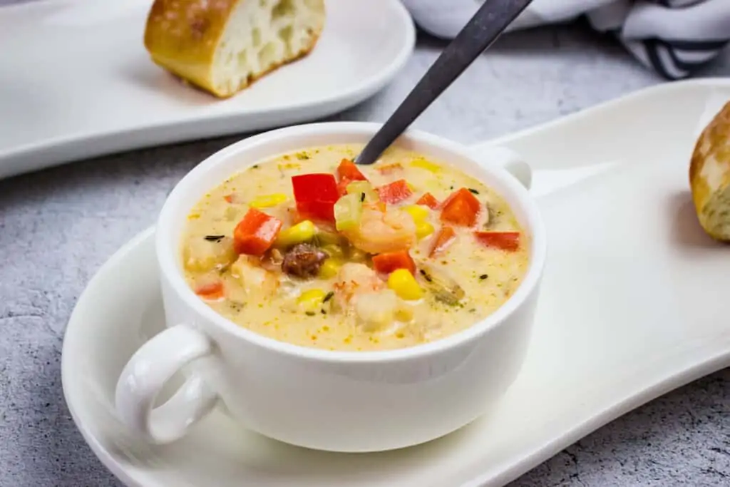 shrimp & Corn chowder with chipotle in a serving bowl with a heel of crusty bread nearby