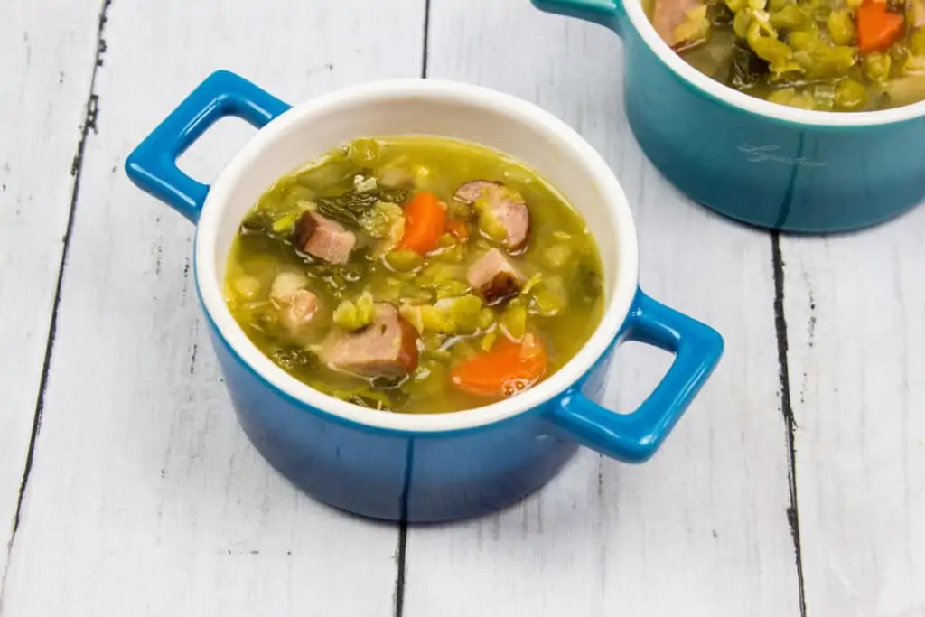 Two bowls of soup on a wooden table.
