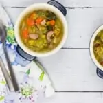split pea, ham and sausage soup in two small bowls with spoons and a napkin