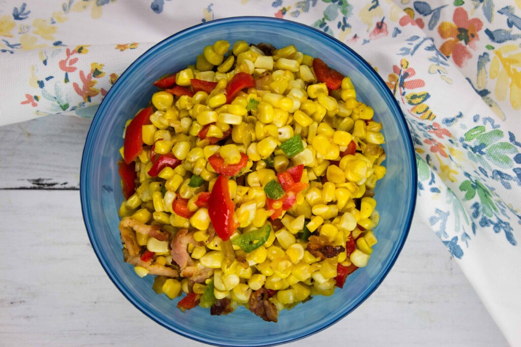 Texas corn succotash in a blue serving bowl with a floral napkin in the background