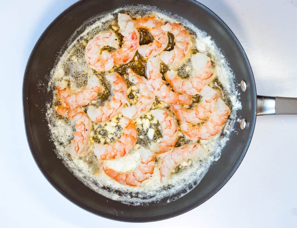 Shrimp added to a skillet with garlic butter.
