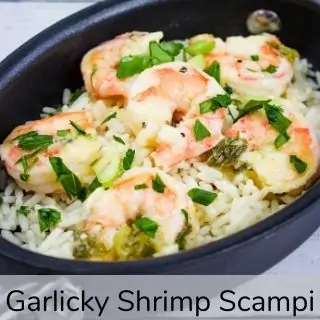 Garlicky shrimp scampi in a black oval dish.