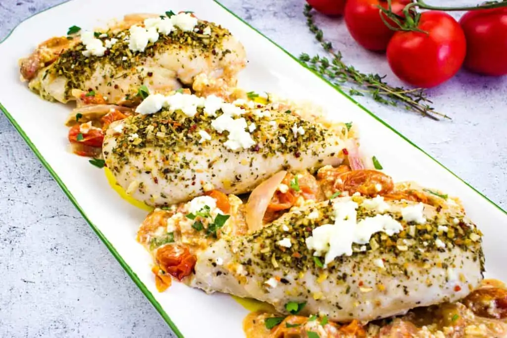 Mediterranean Chicken Bake with feta and tomatoes on a white plate.