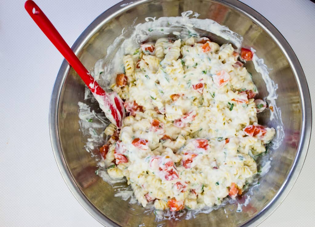 Cheese sauce added to the pasta with tomatoes folded in.