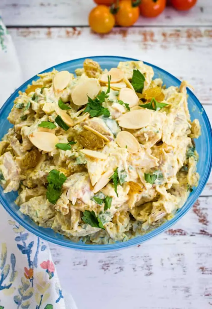 Curried chicken salad with raisins in a blue bowl.