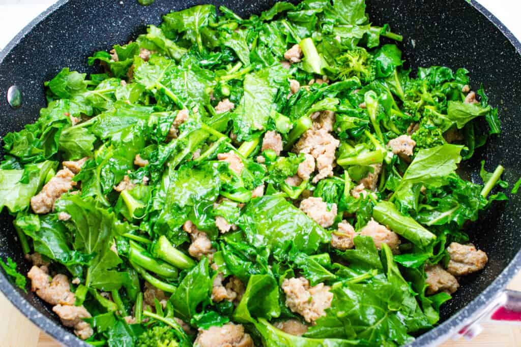 Adding the chopped broccoli rabe to the skillet