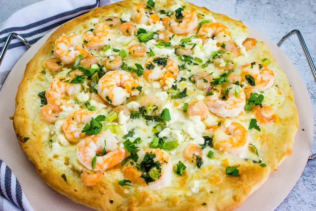 shrimp scampi pizza on a pizza stone