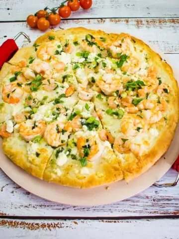 shrimp scampi pizza on a pizza stone