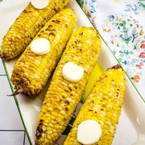Grilled corn on a white platter.