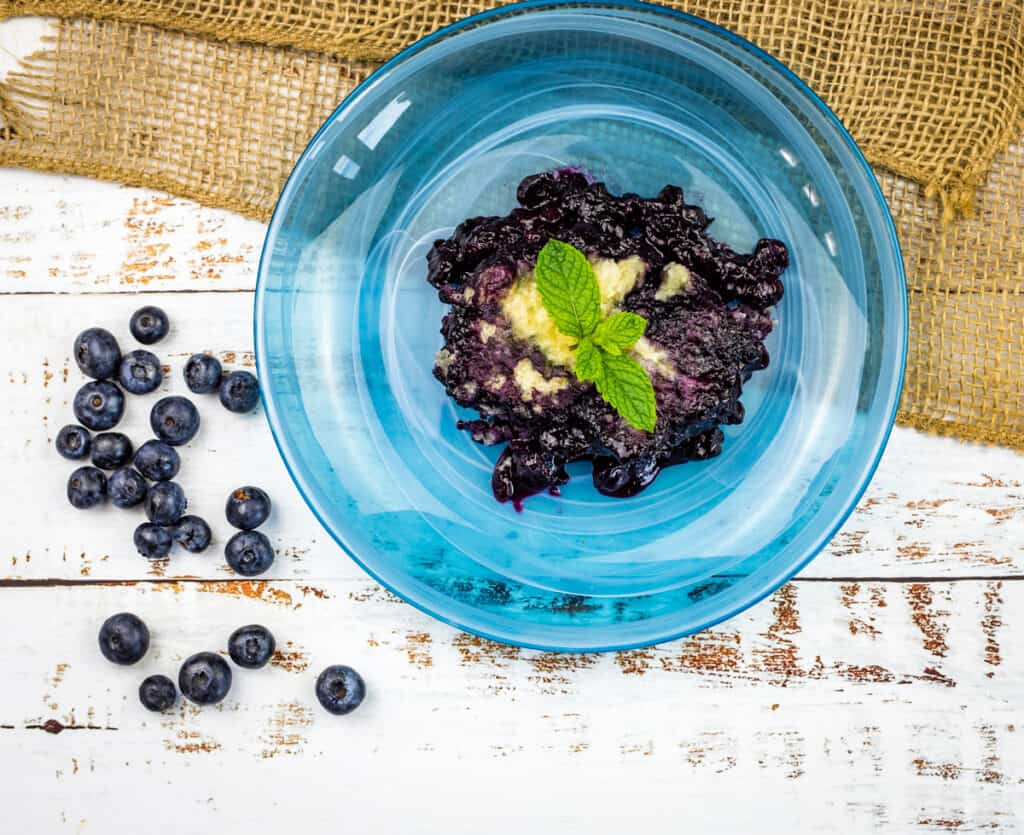 A blue bowl filled with blueberries and mint, creating a delightful blueberry grunt.