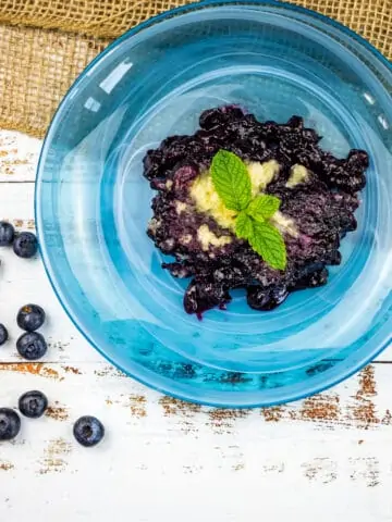 A blue bowl filled with blueberries and mint, creating a delightful blueberry grunt.