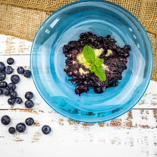 A blue bowl filled with blueberries and mint, creating a delightful blueberry grunt.