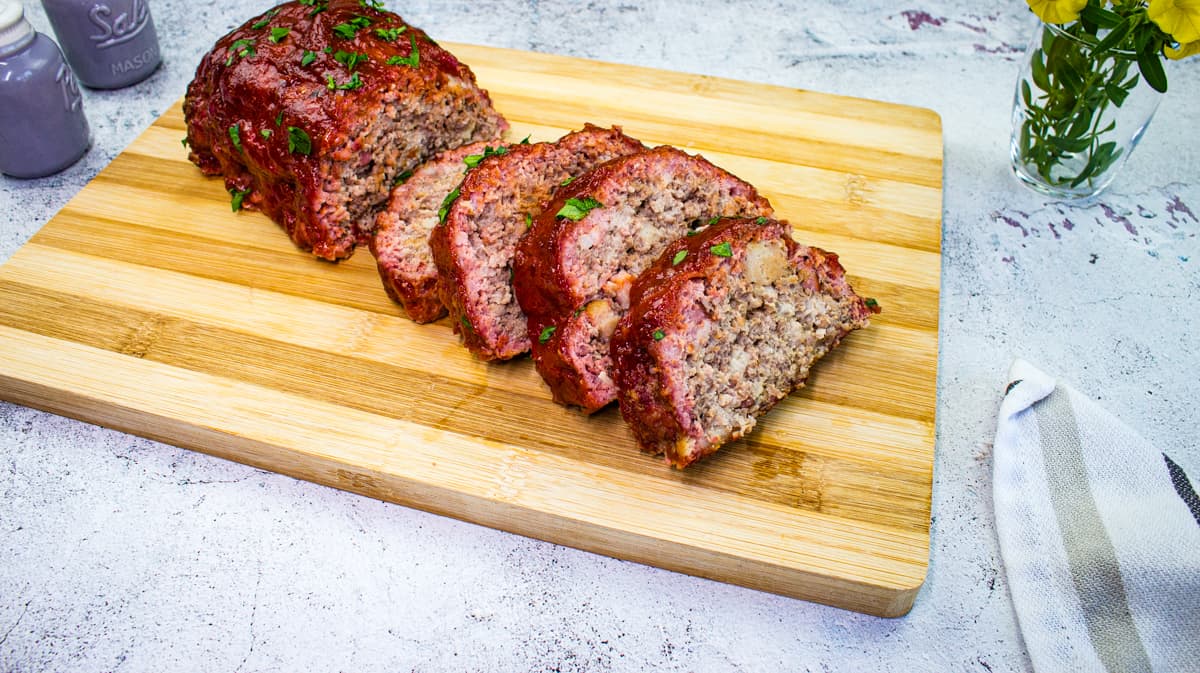 Sliced Smoked Meatloaf on a cutting board with salt and pepper shakers on the side.