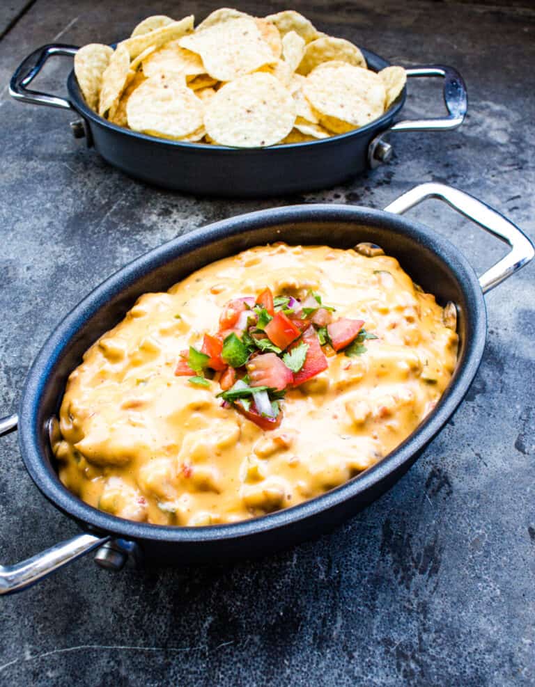 Smoked queso in a black dish with chips in the background.
