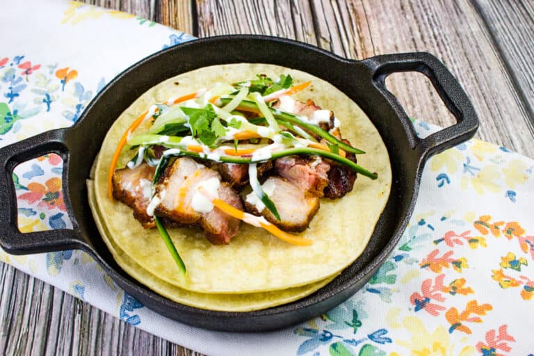 Smoked pork belly tacos with spicy pickled vegetables in a pan.