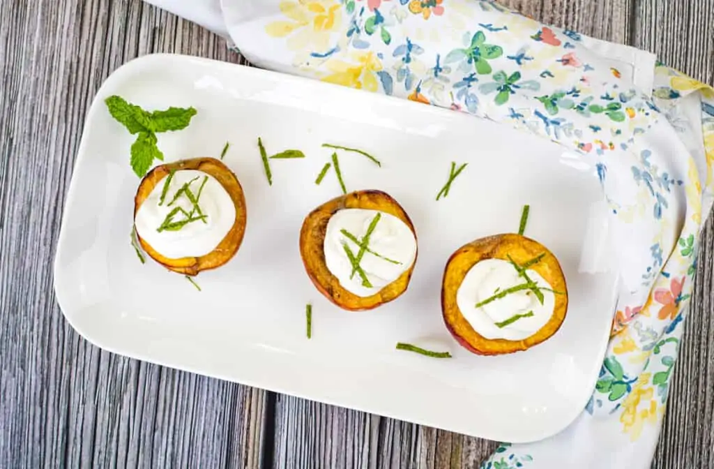 smoked peaches with spice rum whipped cream on a platter