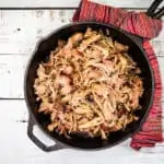 Smoked pulled pork in a skillet on a wooden table.