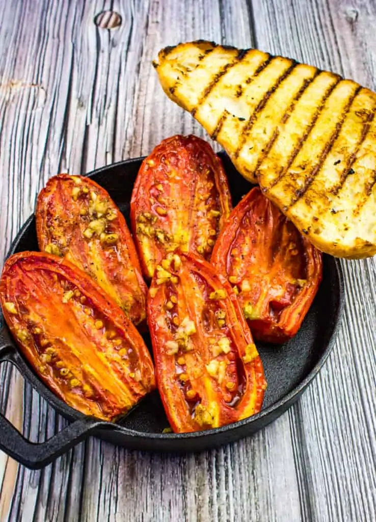 smoked tomatoes in a black bowl with grilled bread on the side