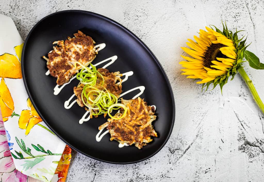 Corned beef fritters garnished with onions and cream.