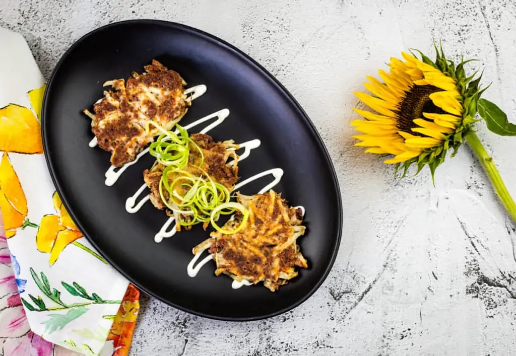 Corned beef fritters garnished with onions and cream.