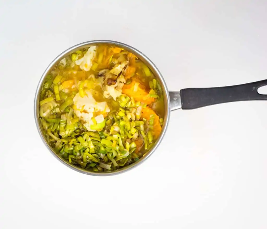 simmering the cauliflower and sweet potato soup ingredients in a pot