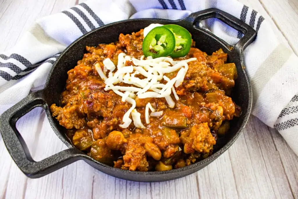 Over the top chili in a bowl with cheese on top.
