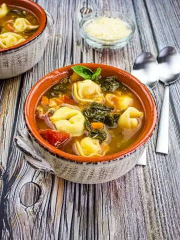 tortellini soup with kale and chicken in a rustic bowl