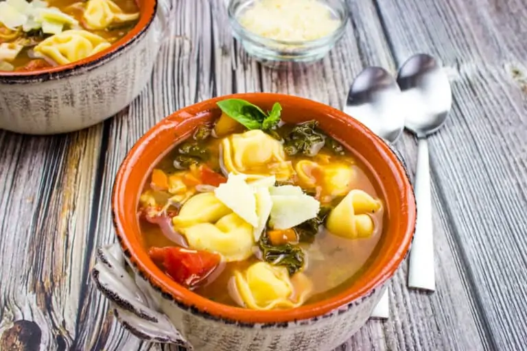 Tortellini soup with cheese on top in a bowl.