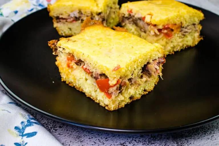 Three slices of pulled pork stuffed cornbread on a black plate.