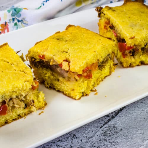 Three slices of pulled pork stuffed cornbread served on a white plate.