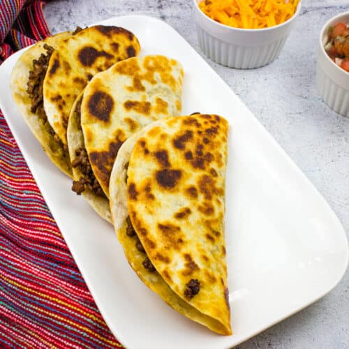 Tacos dorados on a white platter.