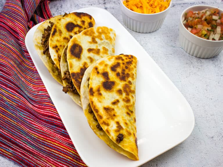 Tacos dorados on a white platter.