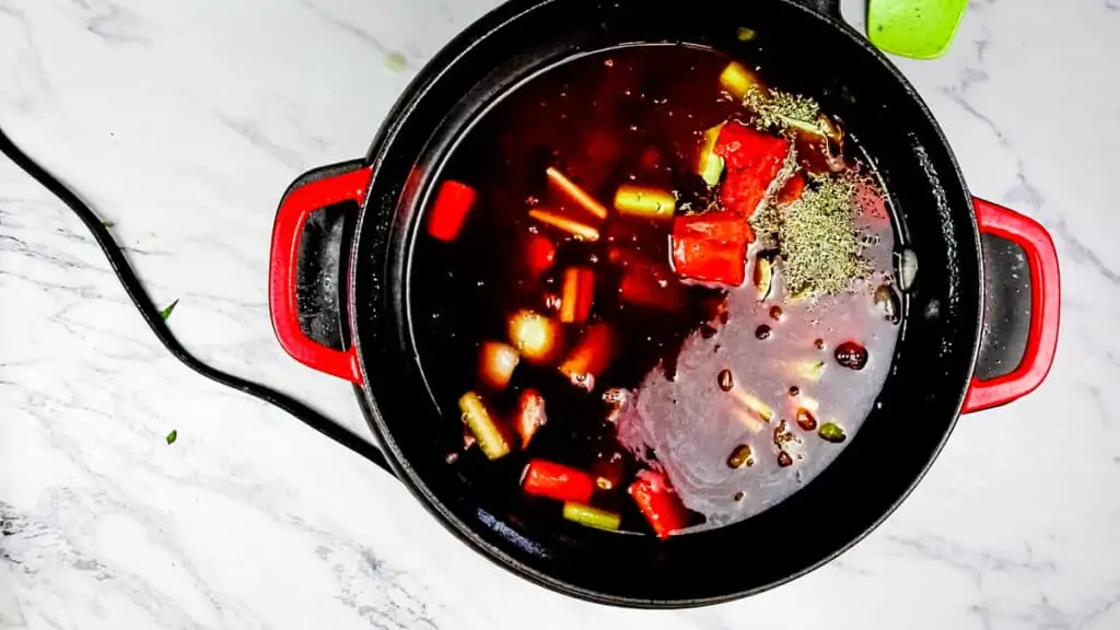 adding the herbs and liquids to the instant pot dutch oven