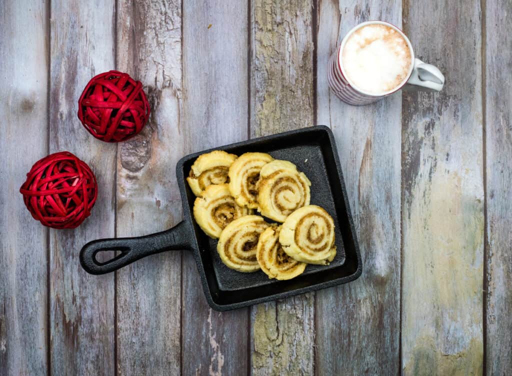 A pan with cinnamon rolls and a cup of coffee on a wooden table.