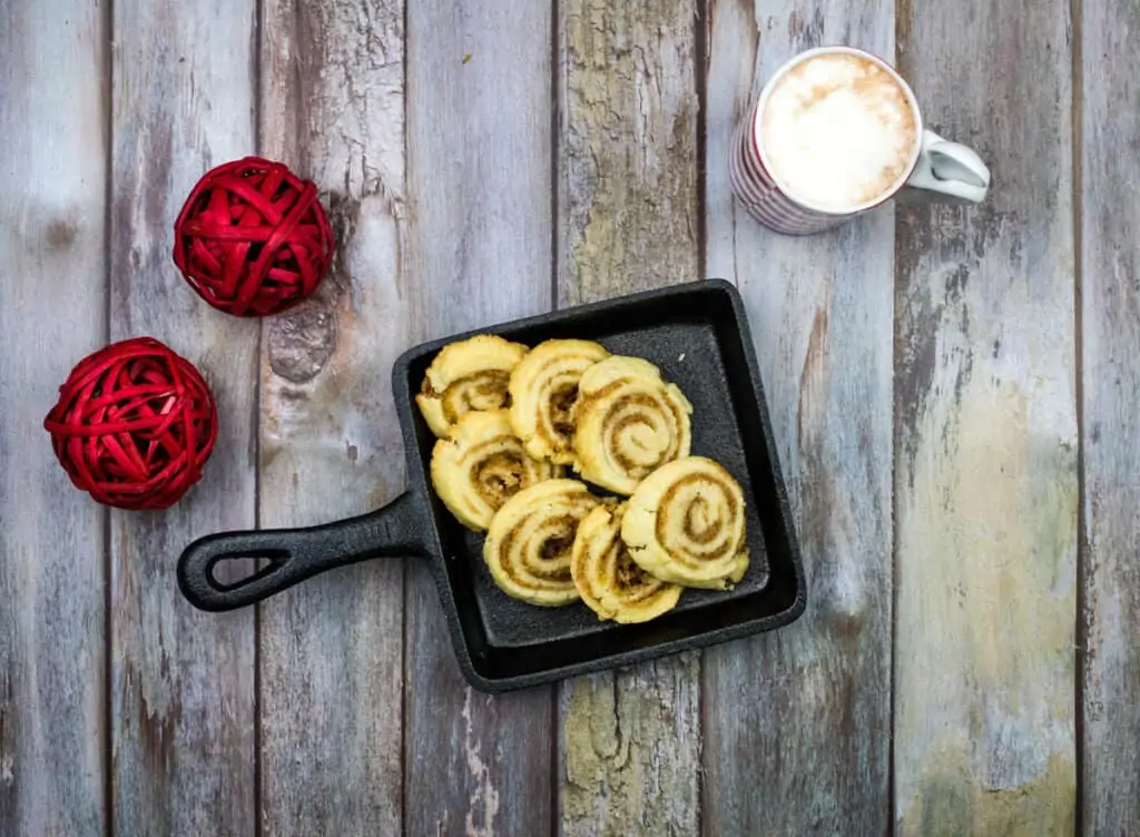 A pan with cinnamon rolls and a cup of coffee on a wooden table.