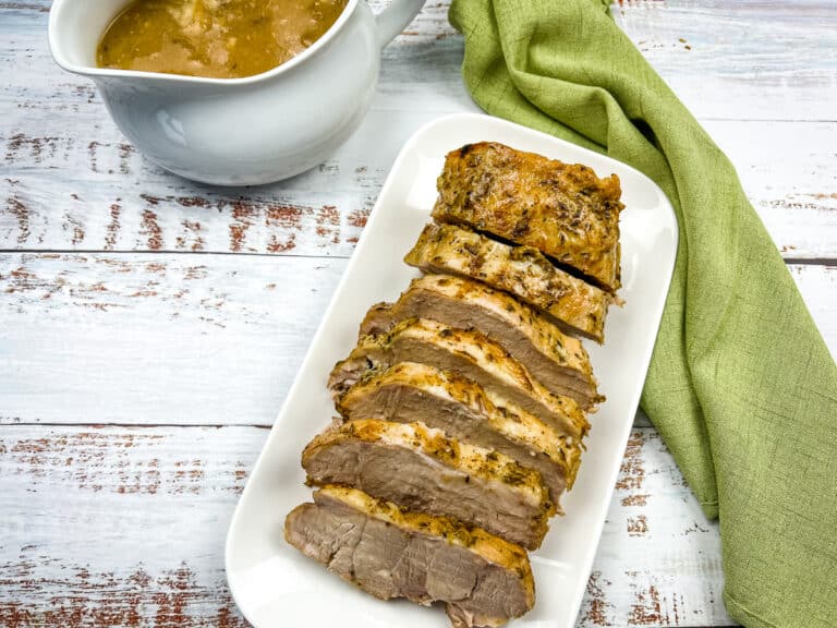 German Pork loin on a plate with gravy to the side.