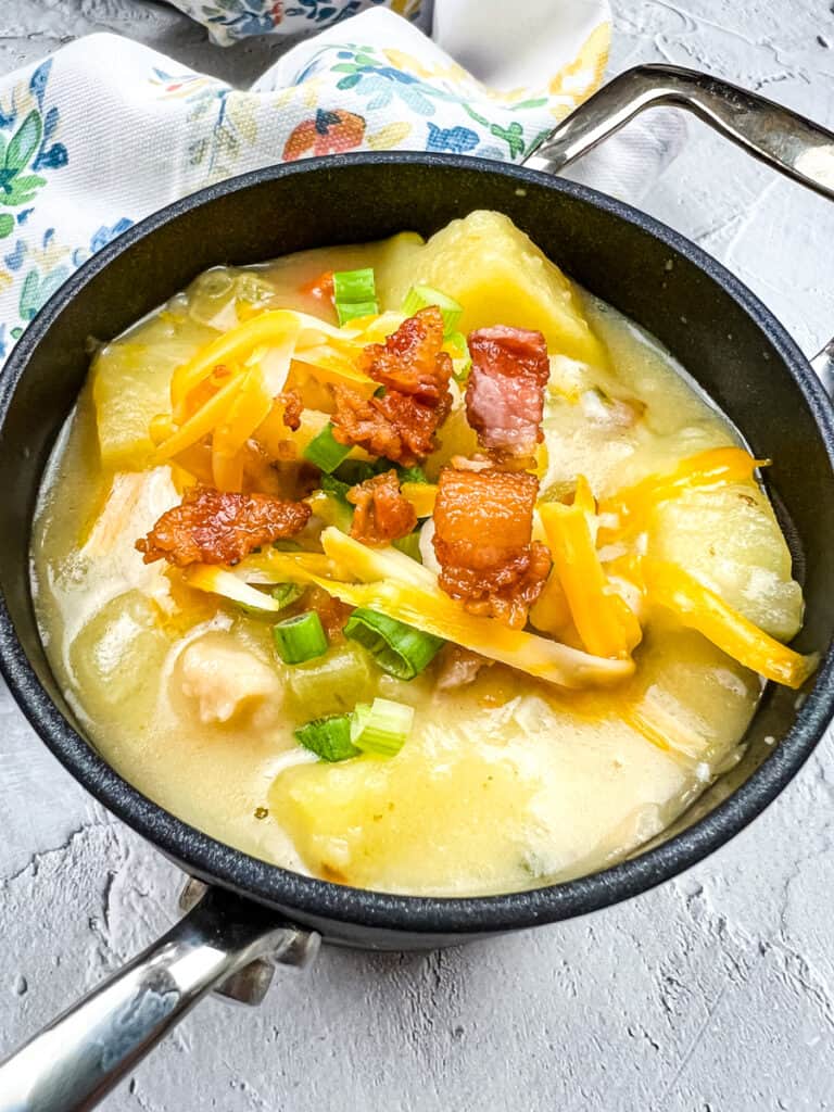 Fully loaded baked potato soup in a black bowl.