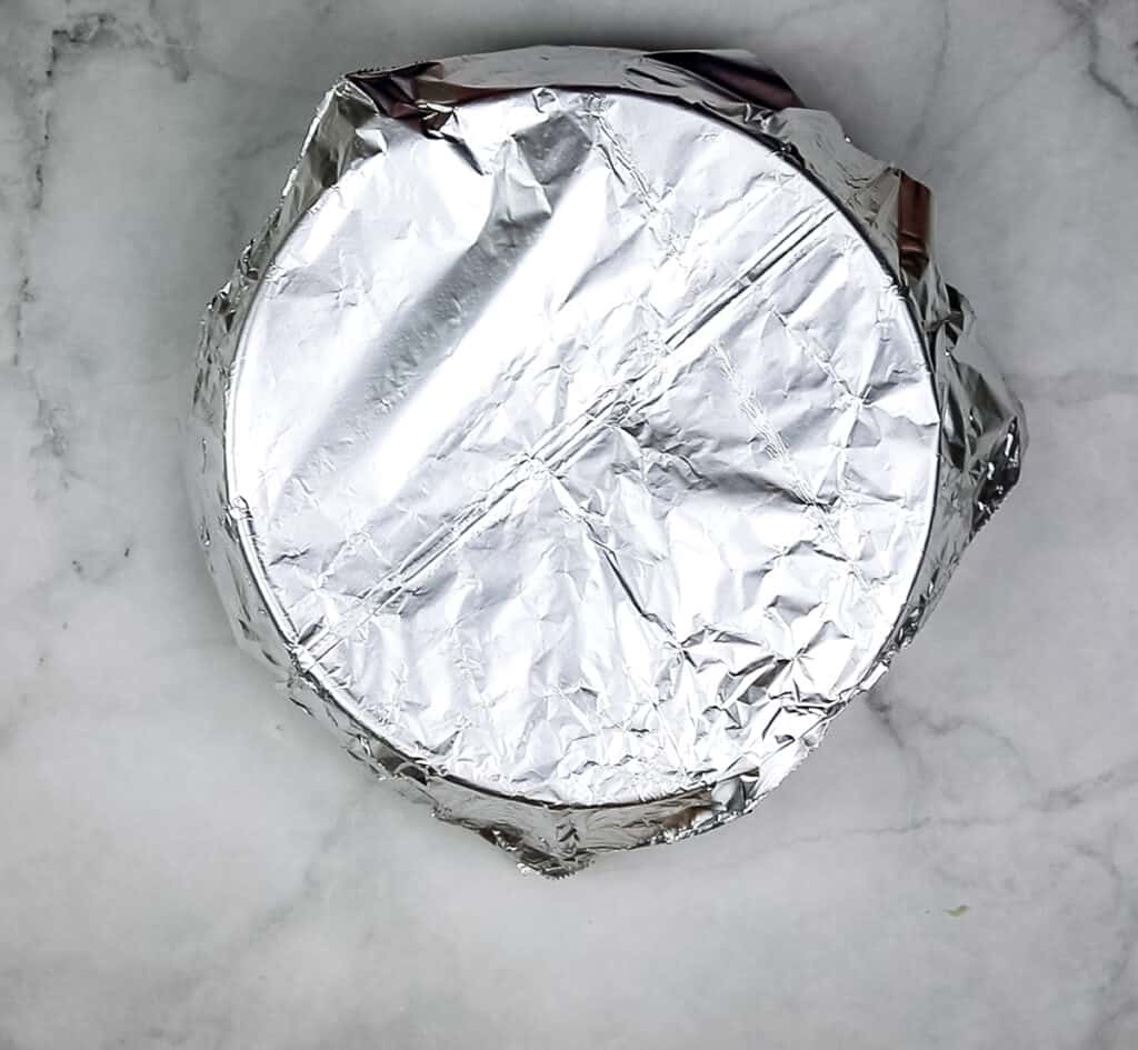 A casserole covered with foil ready for the oven to make sauerkraut with bacon and apples.