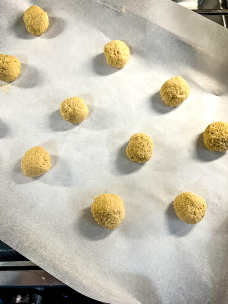 cookie dough balls on a parchment paper lined sheet pan